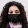 Close up portrait of a young brunette woman with big brown eyes in the medicine mask on her face thinking about virus.
